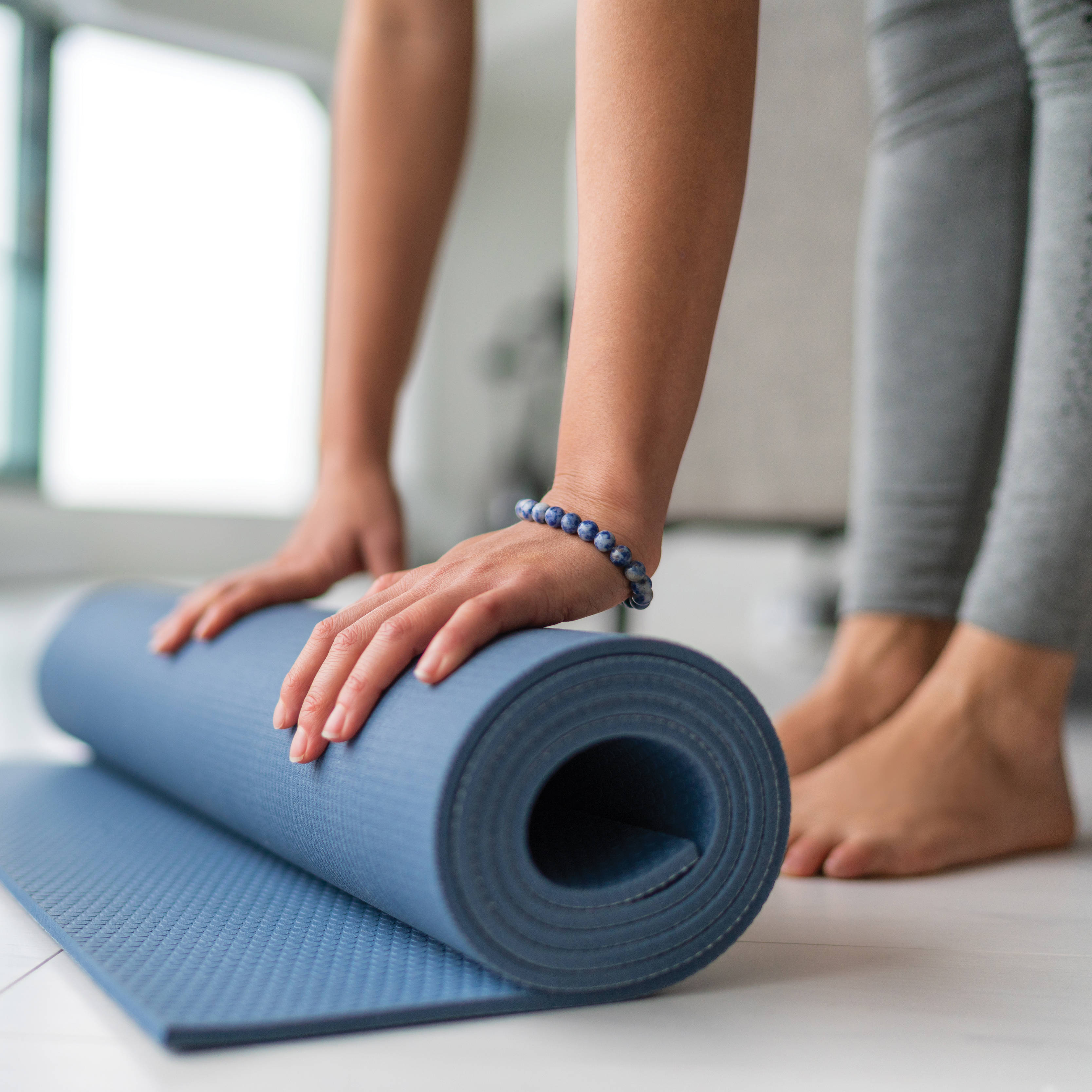 Frau rollt eine Yogamatte zusammen